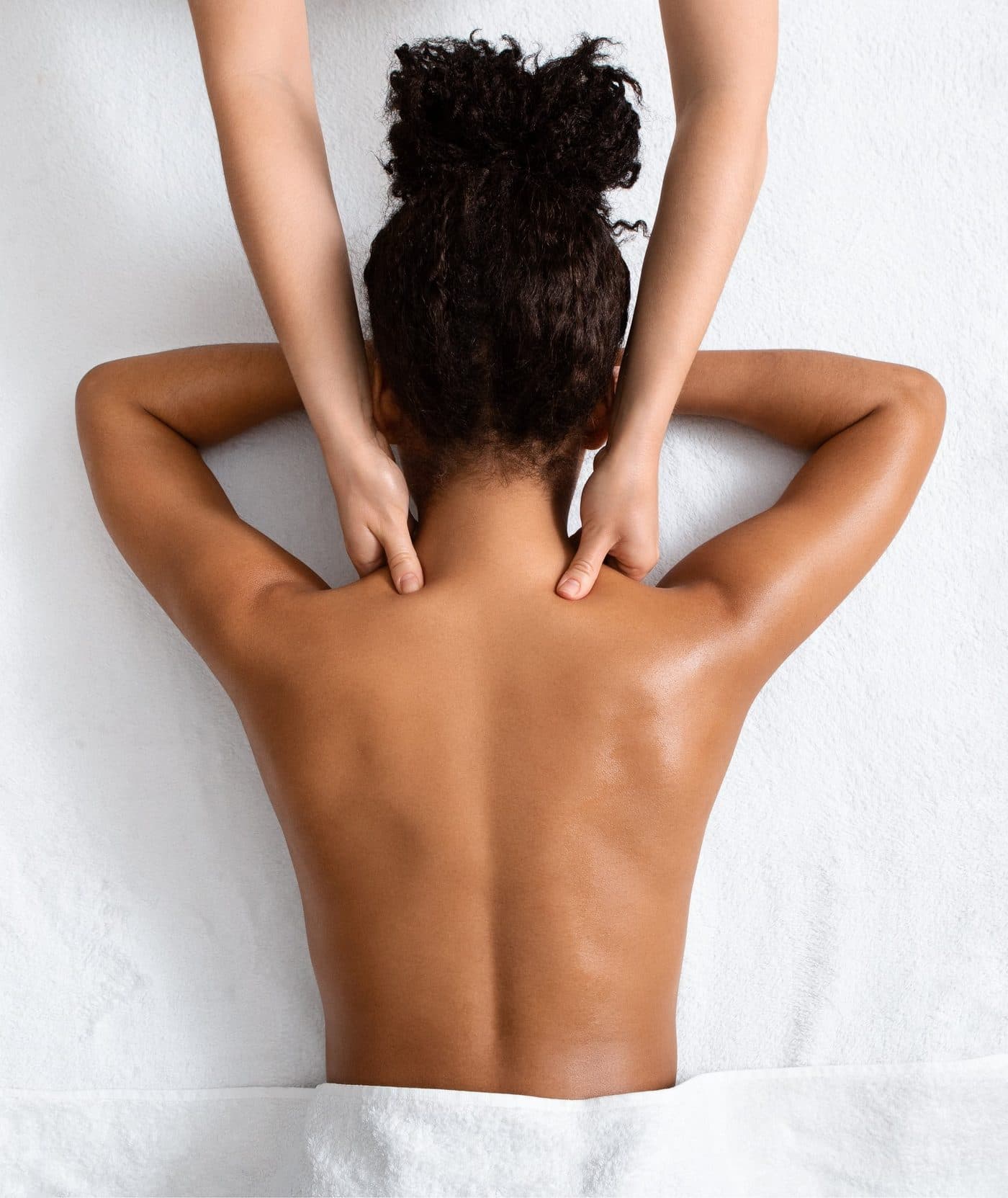 Overhead view of a neck and shoulder massage on a patient lying face down.