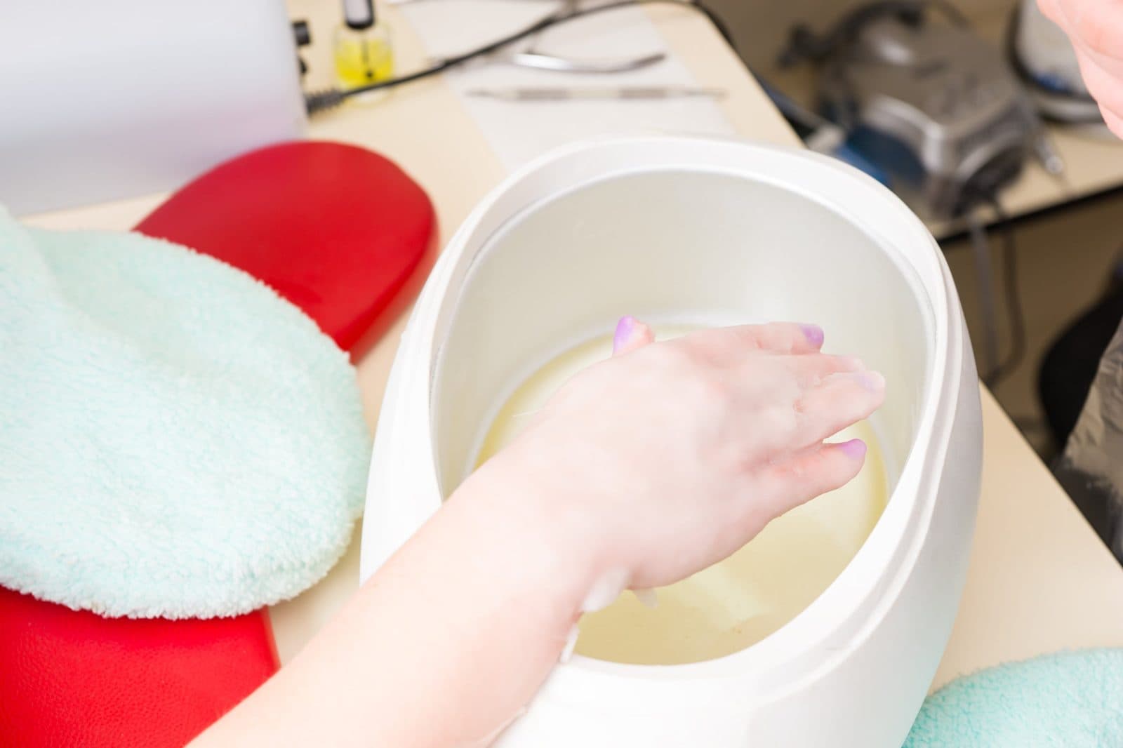 A hand being dipped in a warm paraffin wax bath at the office.